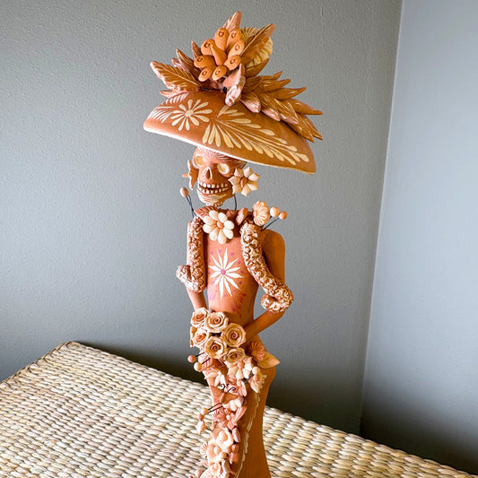 Catrine figurine. collectible item for the Day of the death, It is constructed from clay and features intricate, handcrafted detailss such as a large hat, sloral decorations, and hand-painted skeleton face