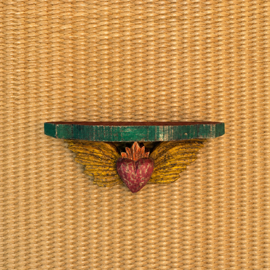 Decorative Mexican folk art wall shelf features a hand-painted wooden "corazon" (heart) with gold wings and a ristic teal red shelf top