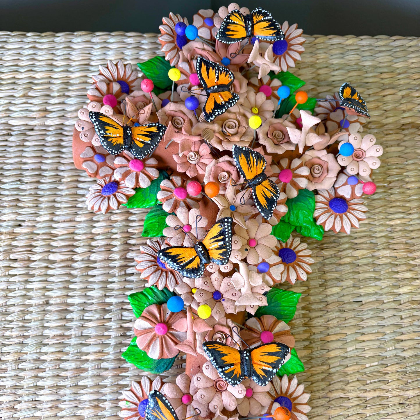 Mexican handcrafted clay wall cross, specifically as a Metepec pottery. Style sculpture adorned with Monarch butterflies and flowers.