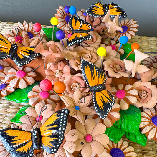 Mexican handcrafted clay wall cross, specifically as a Metepec pottery. Style sculpture adorned with Monarch butterflies and flowers.