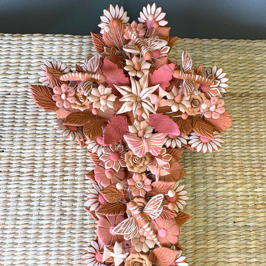 Handmade Mexican pottery clay cross, likely used for wall decor and featuring intricate floral, leaf and butterflies details.