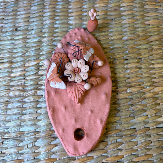 Handcrafted clay "Cactus" with decorative flowers and butterflies in earthy tones.