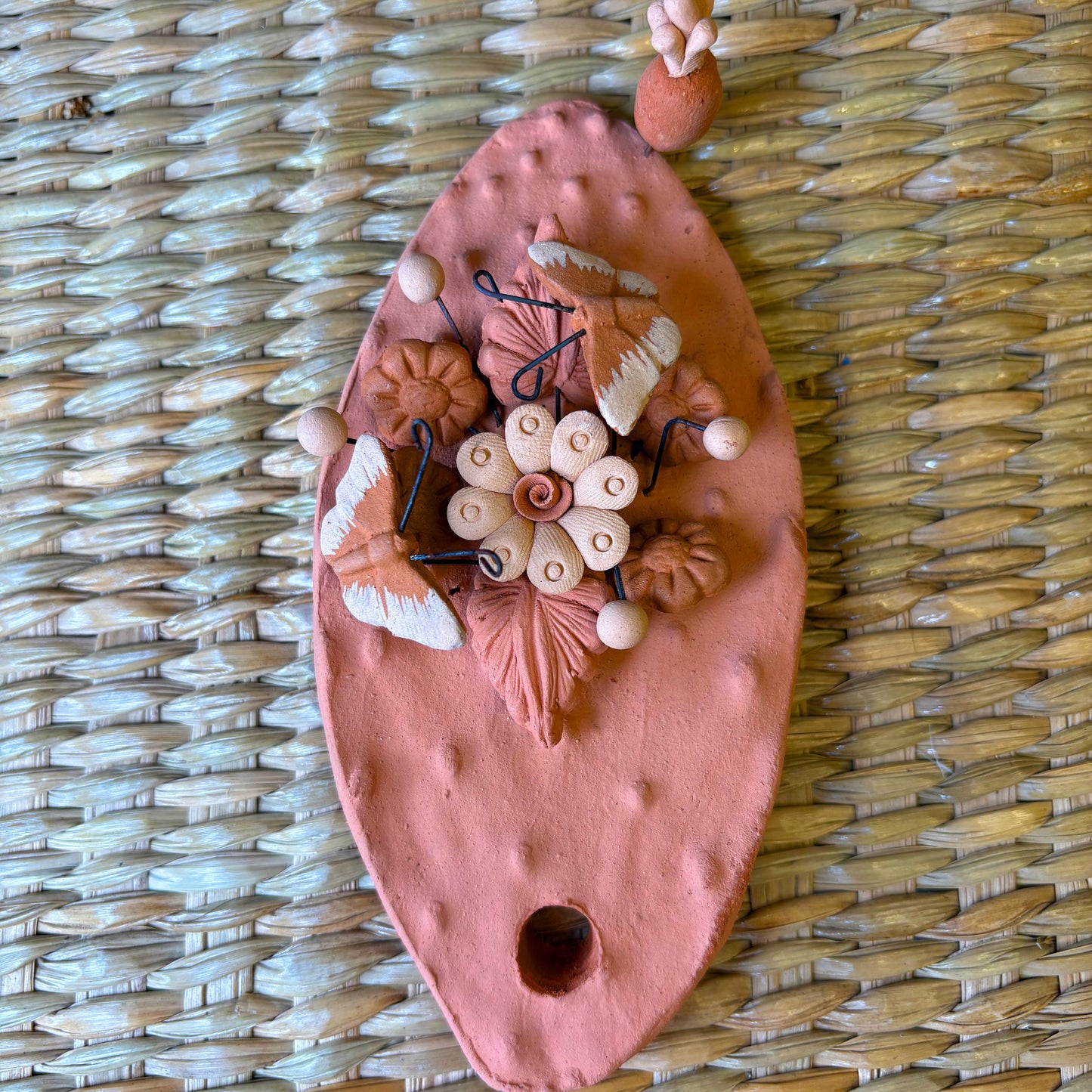 Handcrafted clay "Cactus" with decorative flowers and butterflies in earthy tones.