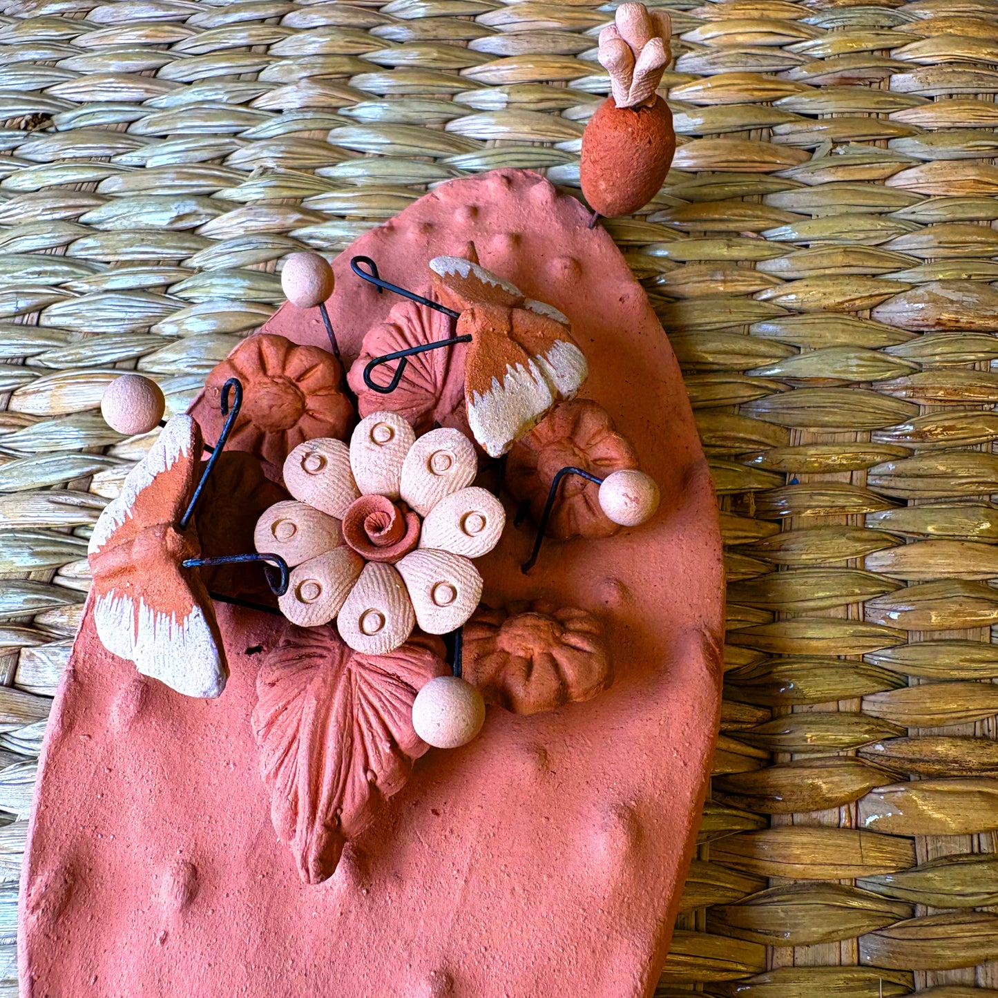 Handcrafted clay "Cactus" with decorative flowers and butterflies in earthy tones.