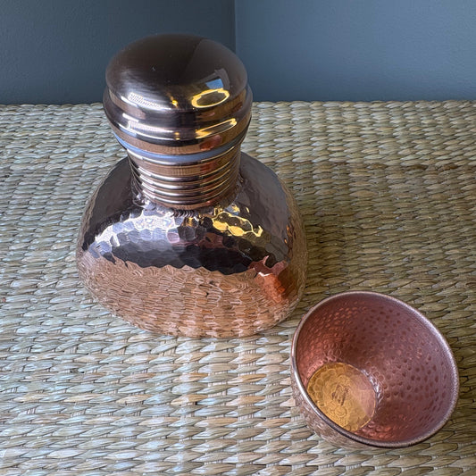 Decorative hammered copper water pot with a matching cup. Popular for home decor and for storing drinking water, wuth some traditional beliefs suggestings health benefits.