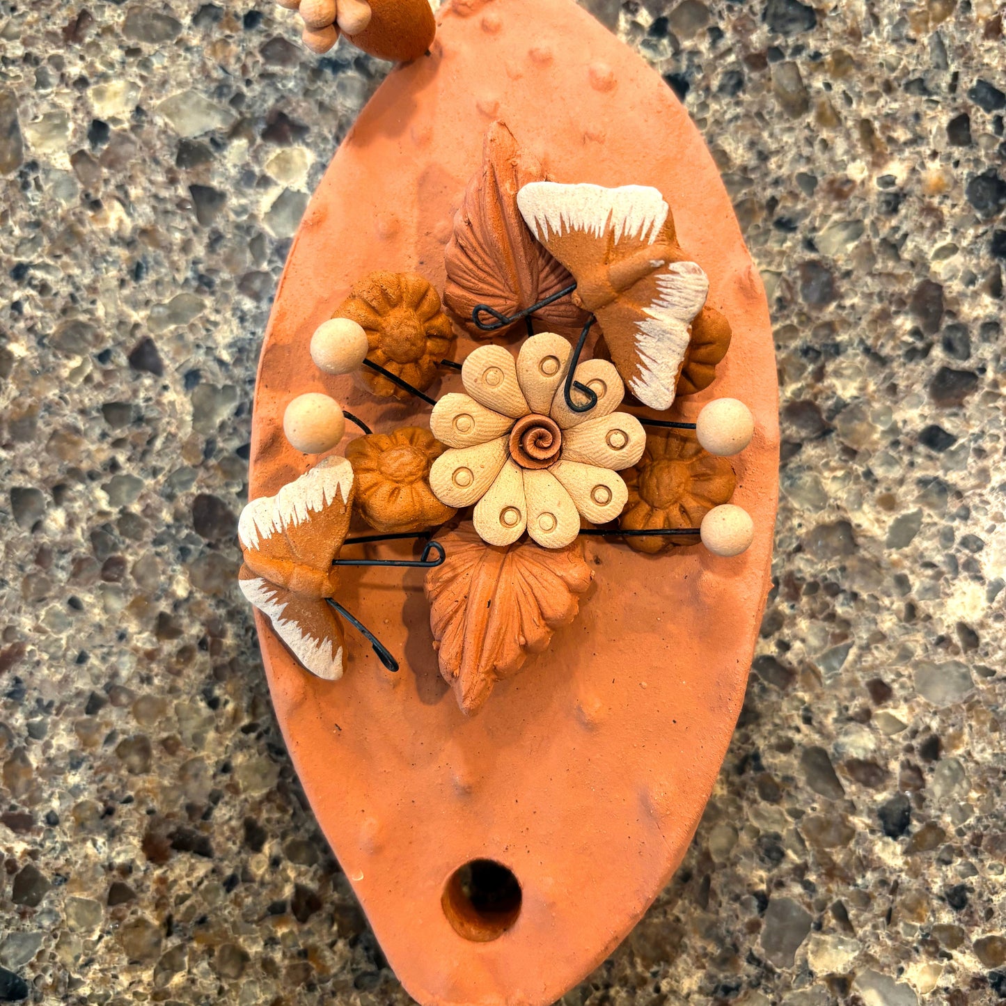 Handcrafted clay "Cactus" with decorative flowers and butterflies in earthy tones.