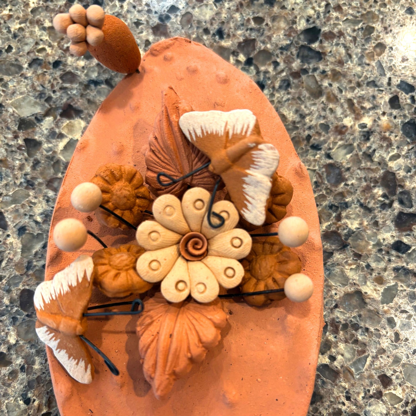 Handcrafted clay "Cactus" with decorative flowers and butterflies in earthy tones.